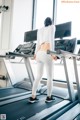 A woman is running on a treadmill in a gym.