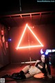 A woman laying on the ground in front of a neon sign.