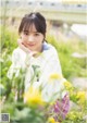 A young woman sitting in a field of yellow flowers.