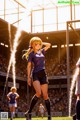 A woman in a blue shirt and black shorts standing on a soccer field.