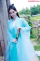 A woman in a blue dress holding a wooden stick.