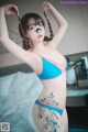 A woman in a blue and pink bikini posing on a bed.