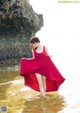 A woman in a red dress standing in the water.