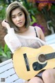 A woman sitting on a bench holding a guitar.