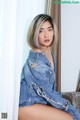 A woman in a denim jacket sitting on a couch.