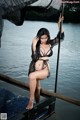 A woman in a black lingerie standing on a dock.