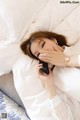 A woman laying in bed talking on a cell phone.