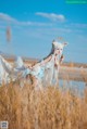 A woman in a white dress is standing in a field.