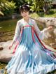 A woman in a blue and white hanbok is posing for a picture.