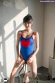 A woman in a blue and red swimsuit sitting on a stool.