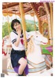 A woman in a school uniform sitting on a carousel.