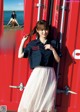 A woman standing in front of a red shipping container.