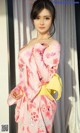 A woman in a pink and yellow kimono posing for a picture.