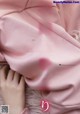 A woman laying on top of a bed covered in pink sheets.