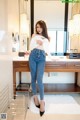 A woman standing in front of a mirror in a bathroom.