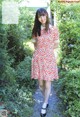 A woman in a red and white dress walking down a path.