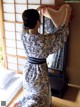 A woman in a blue and white kimono standing in front of a mirror.