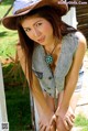 A woman in a cowboy hat leaning against a fence.