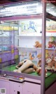 A woman laying on the floor in front of a display case filled with stuffed animals.