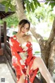 A woman in a red kimono sitting on a bench.