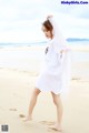 A woman in a white dress is walking on the beach.