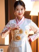 A woman in a white and pink cheongsam posing for a picture.