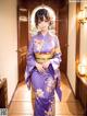 A woman in a purple kimono standing in a hallway.