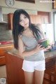 A woman holding a watermelon in a kitchen.