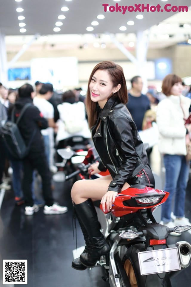 A woman sitting on top of a red motorcycle.
